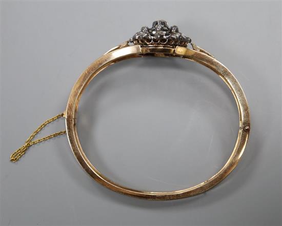 An early 20th century pierced yellow metal and diamond cluster set hinged bracelet, with safety chain, gross 21.7 grams.